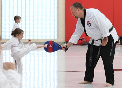 Alliance Police Officer Roy Tittle helps a girl work on her kicks.